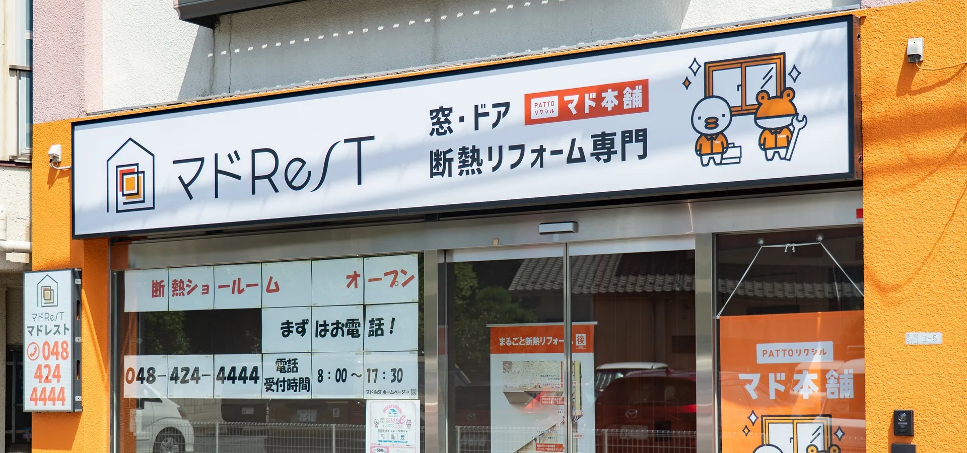 「窓・ドア 断熱リフォーム専門」の看板が掛かるマドレストの店舗外観