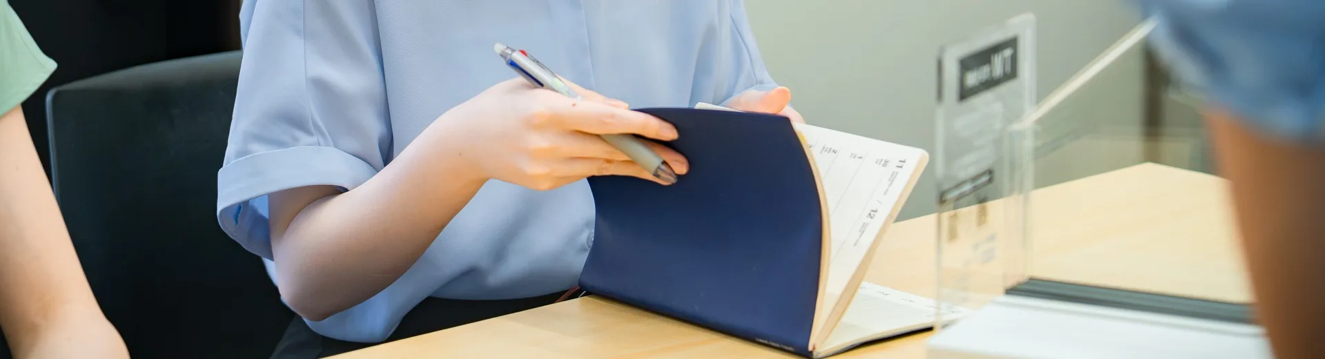 相談内容を手帳に書き留めるマドレストのスタッフの手元
