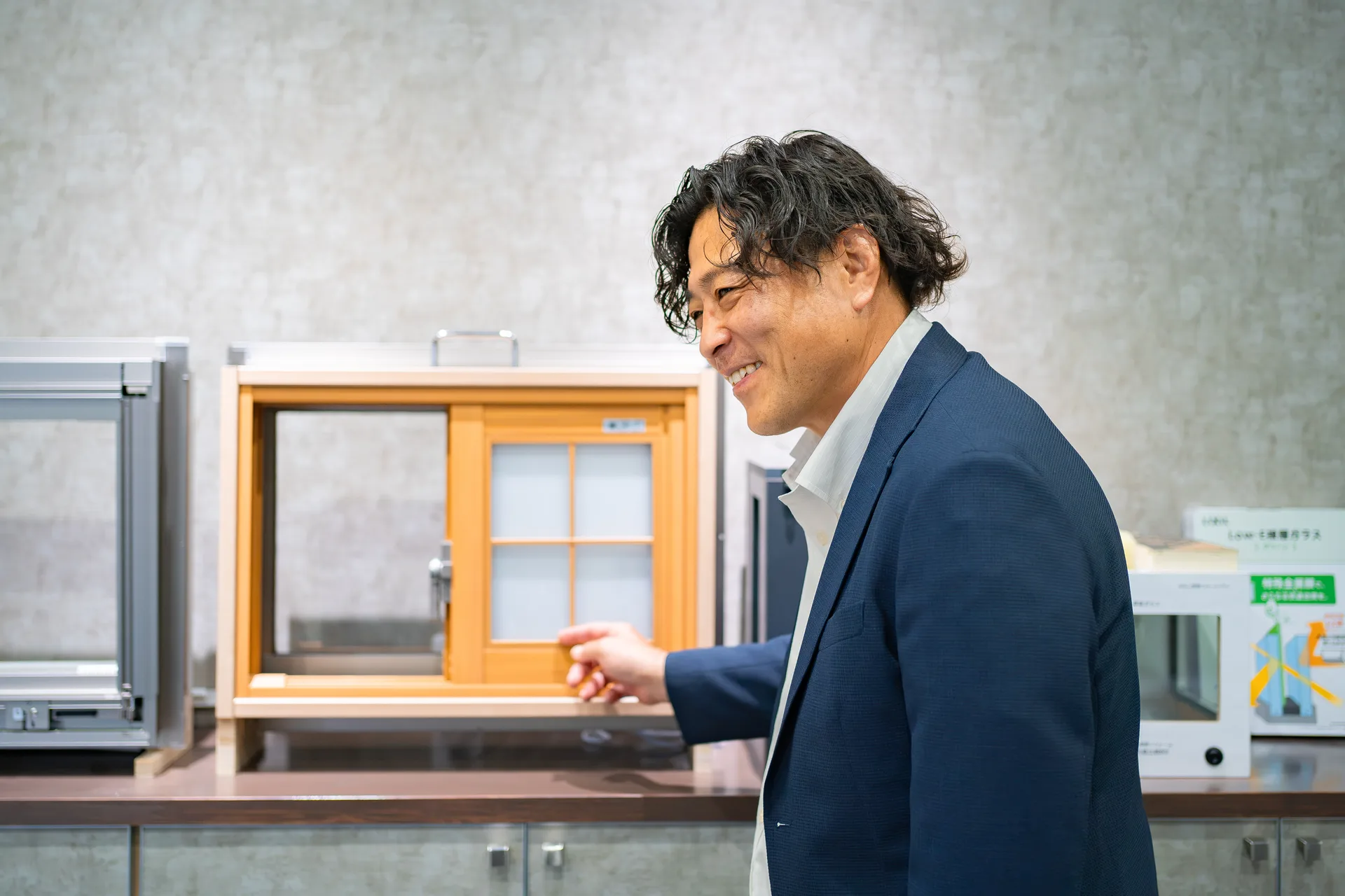 ショールームで内窓の実物を手で示しながら説明するマドレストのスタッフ
